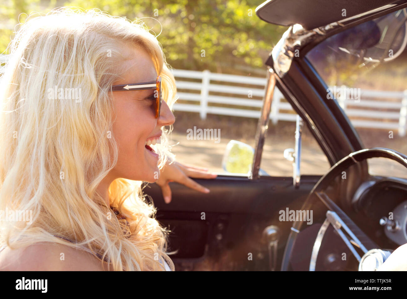 Cheerful woman sitting in convertible car Banque D'Images