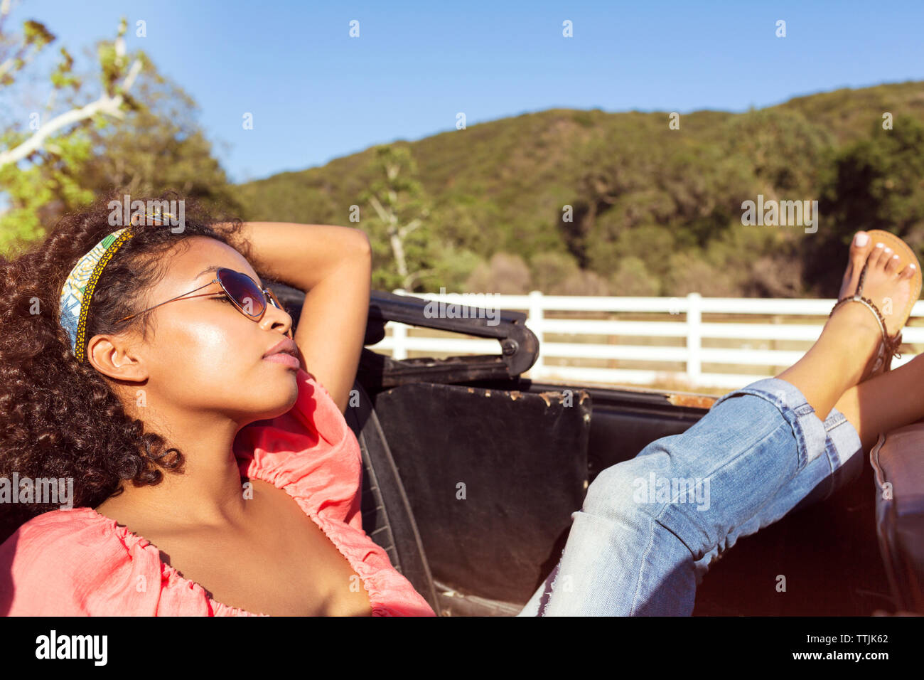 Woman relaxing while sitting in convertible car Banque D'Images