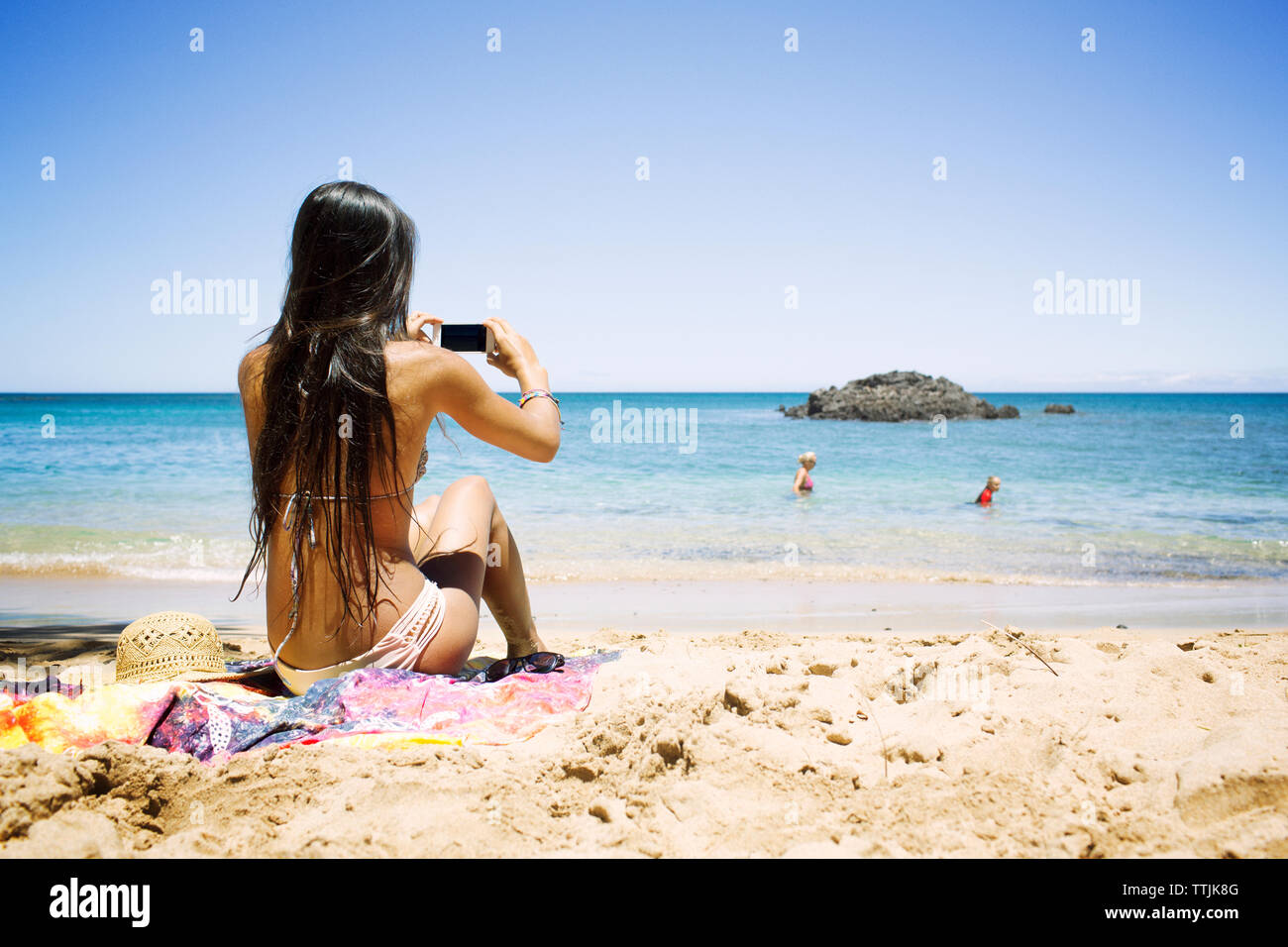Rear view of woman photographing at beach Banque D'Images