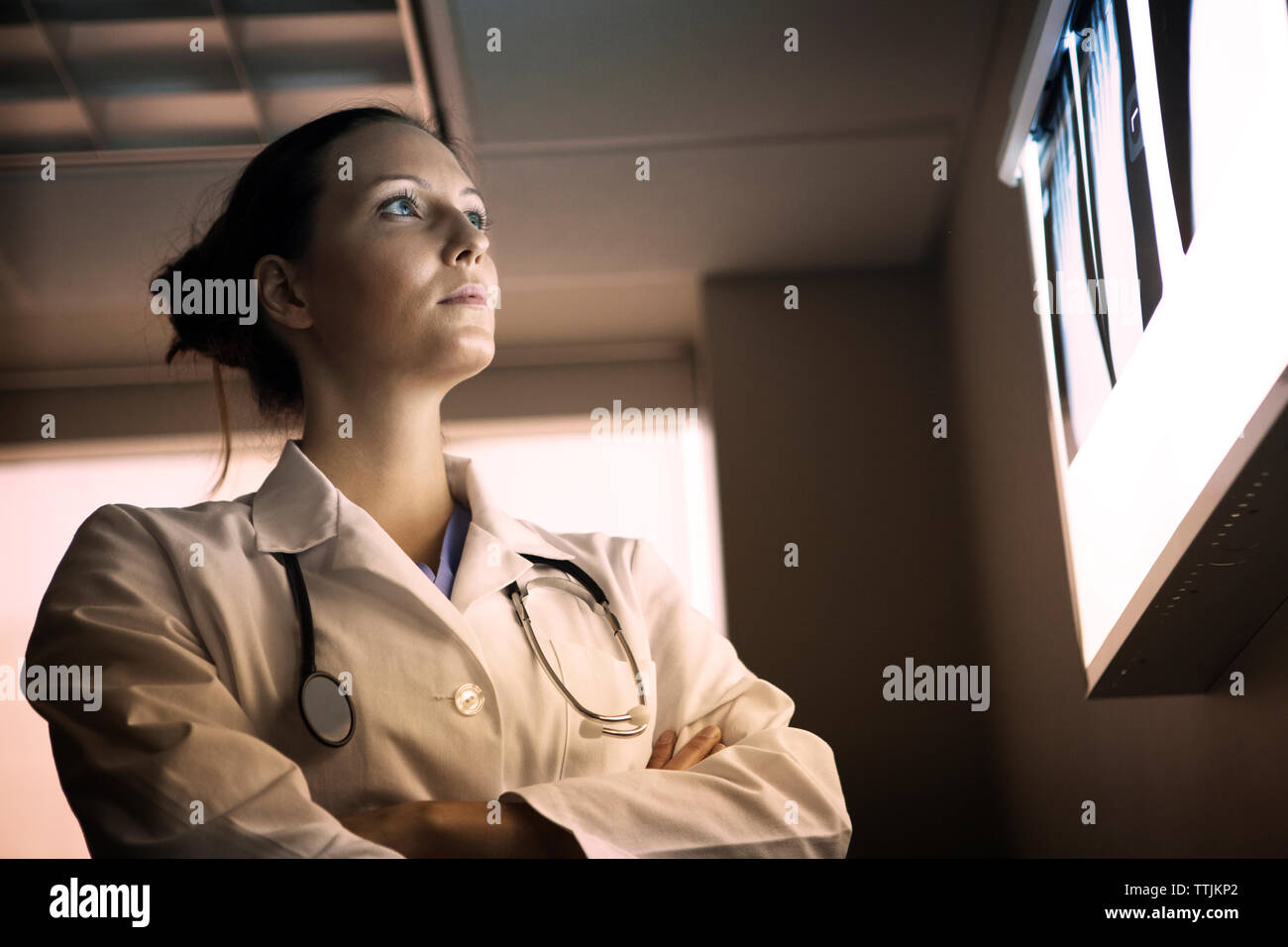 Low angle view of doctor with arms crossed looking at x-ray Banque D'Images