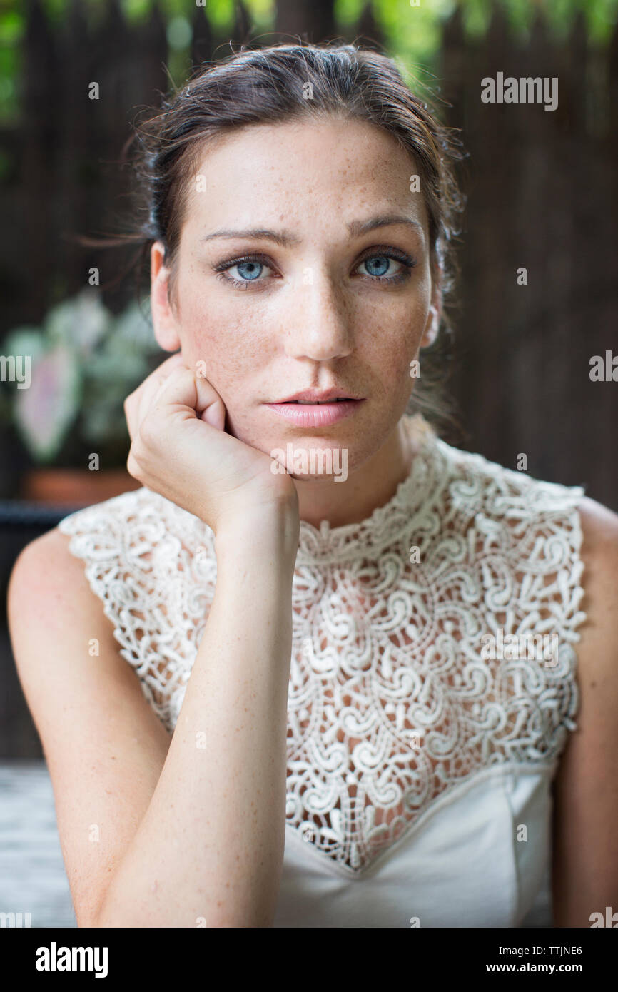 Portrait of woman with hand on chin sitting in restaurant Banque D'Images