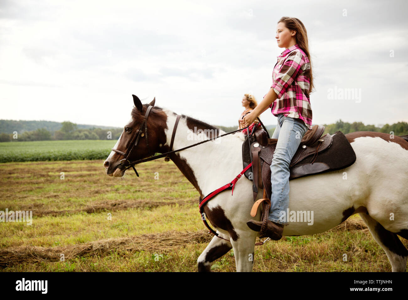 Vue latérale des cowgirls équitation à cheval Banque D'Images