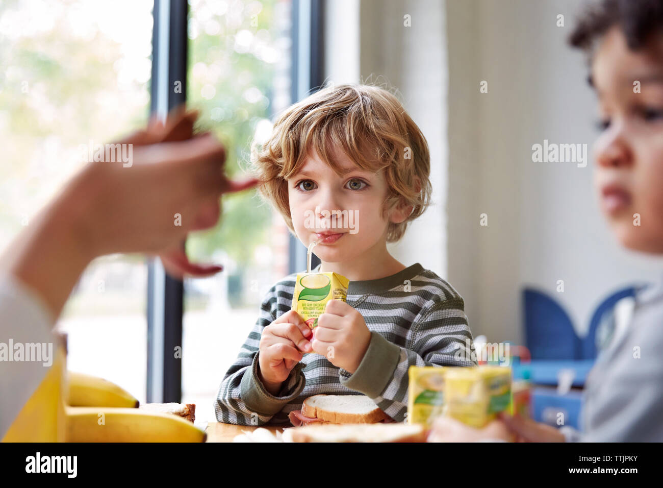 Les garçons de boire des jus de fruits à table durant le repas en maternelle Banque D'Images