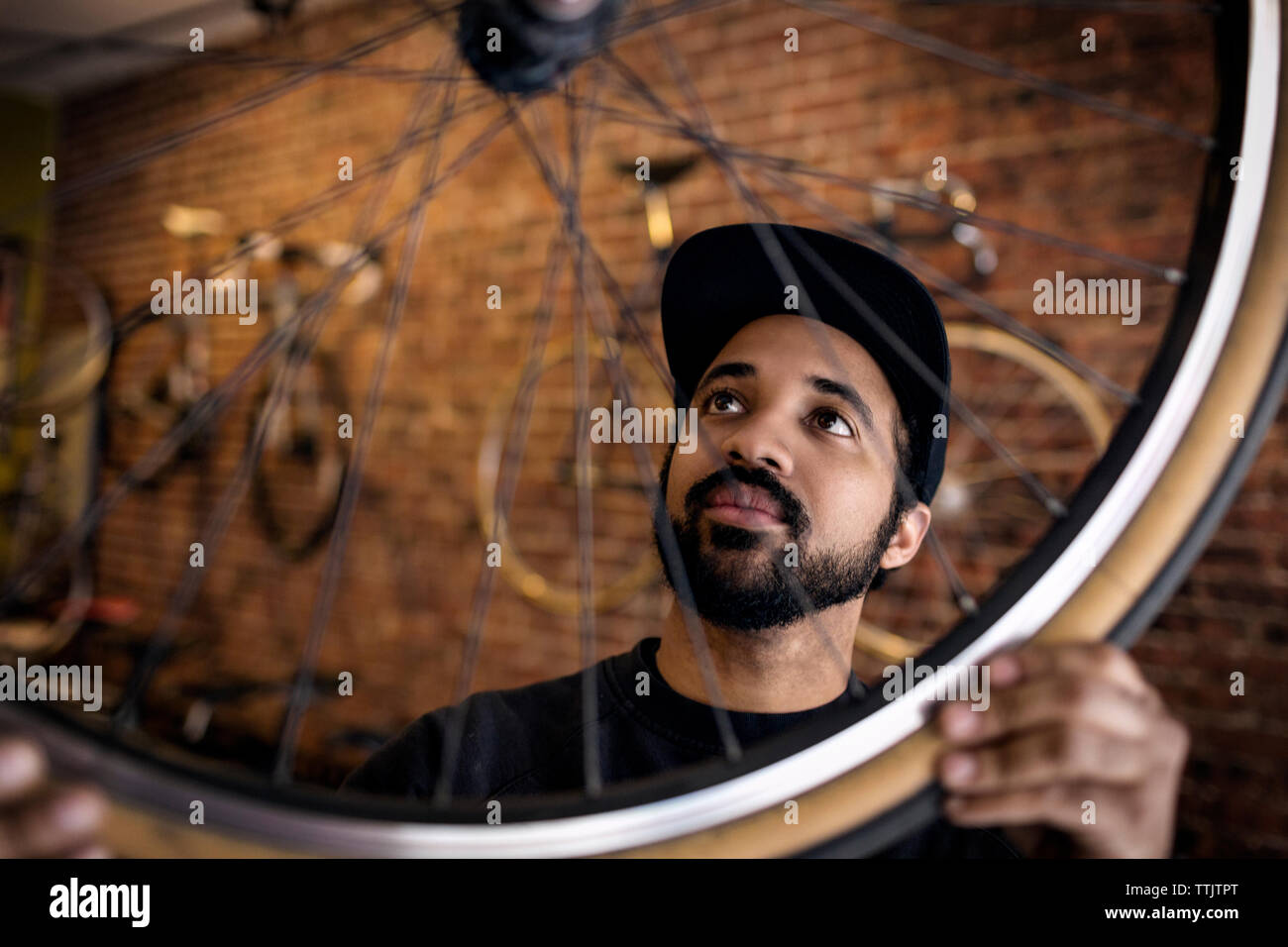 L'homme examinant roue de vélo tout en se tenant à l'atelier Banque D'Images