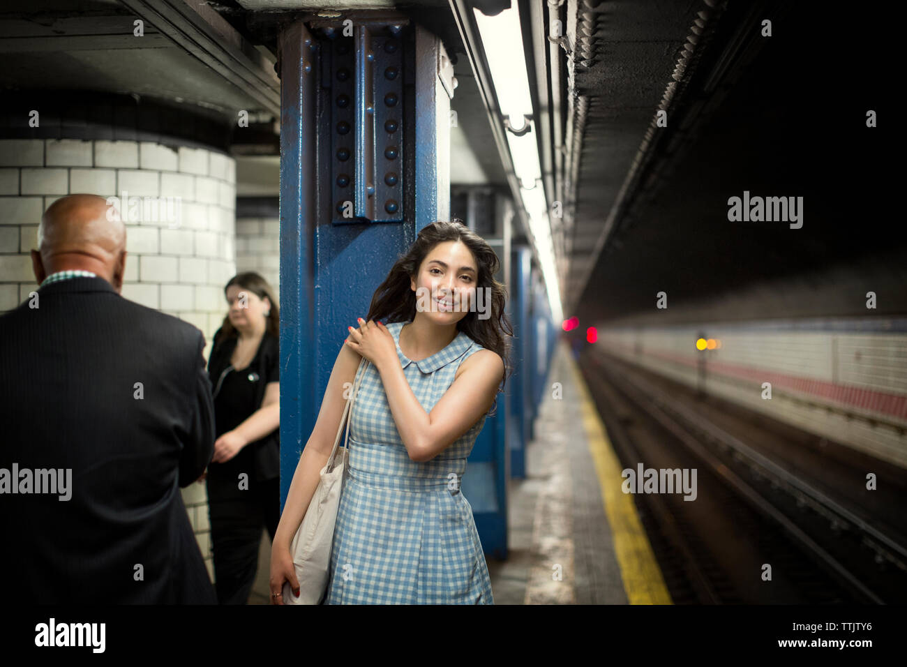 Femme souriante en attente de train dans le métro Banque D'Images