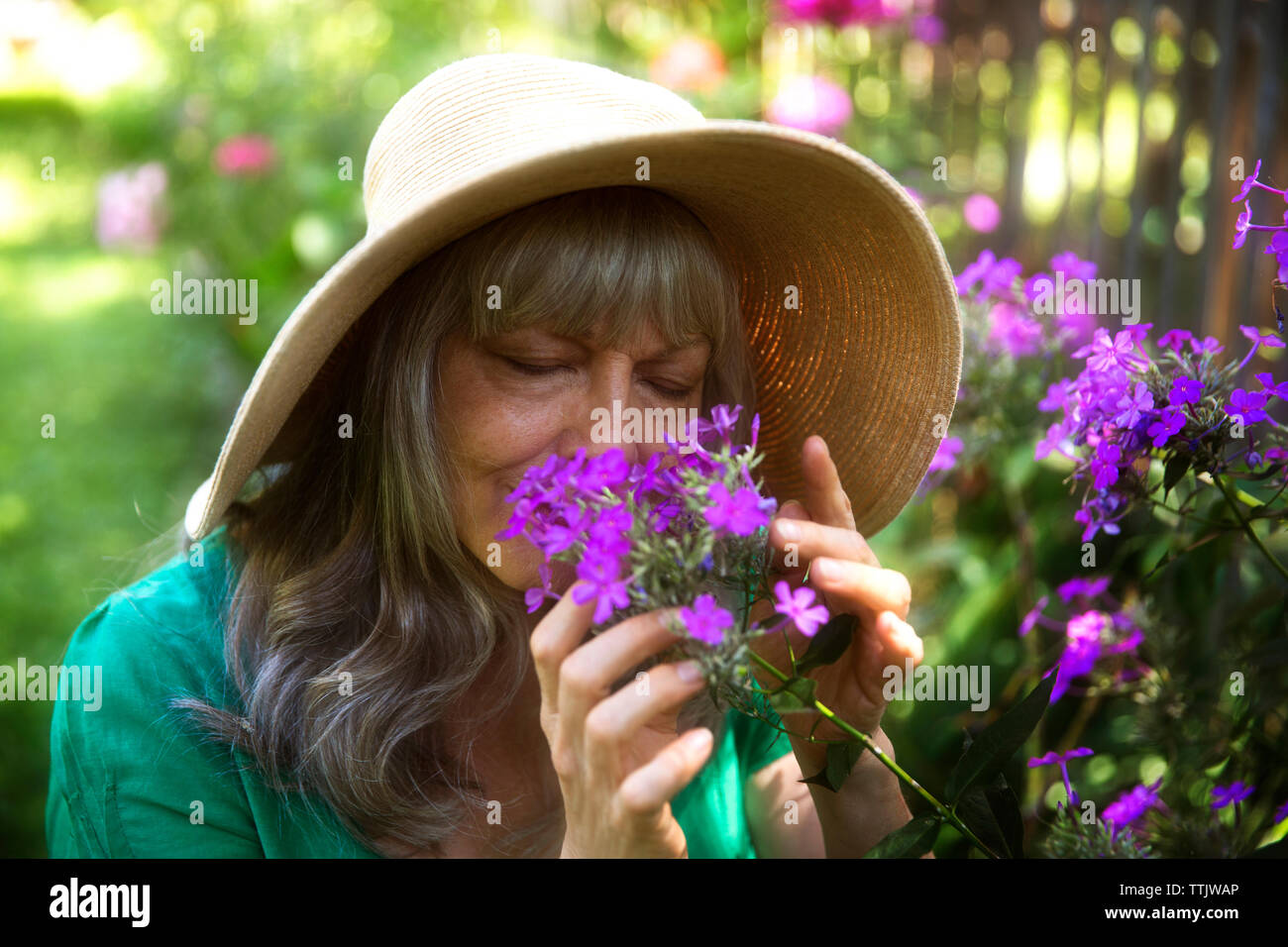 Senior woman with eyes closed smelling fleurs violettes dans le jardin Banque D'Images