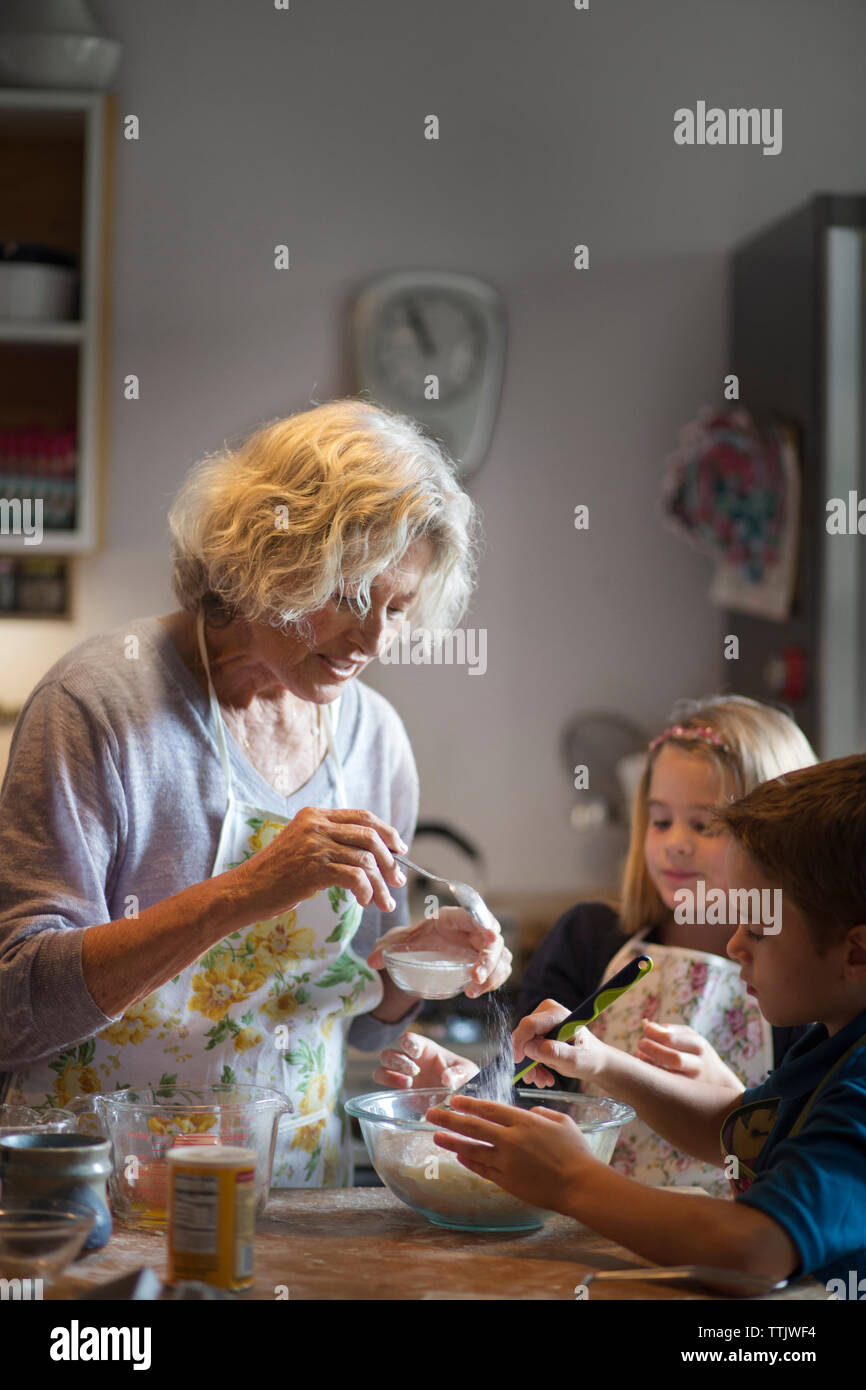 Ajouter la pâte à sucre femme tout en faisant des cookies avec des enfants dans la cuisine Banque D'Images