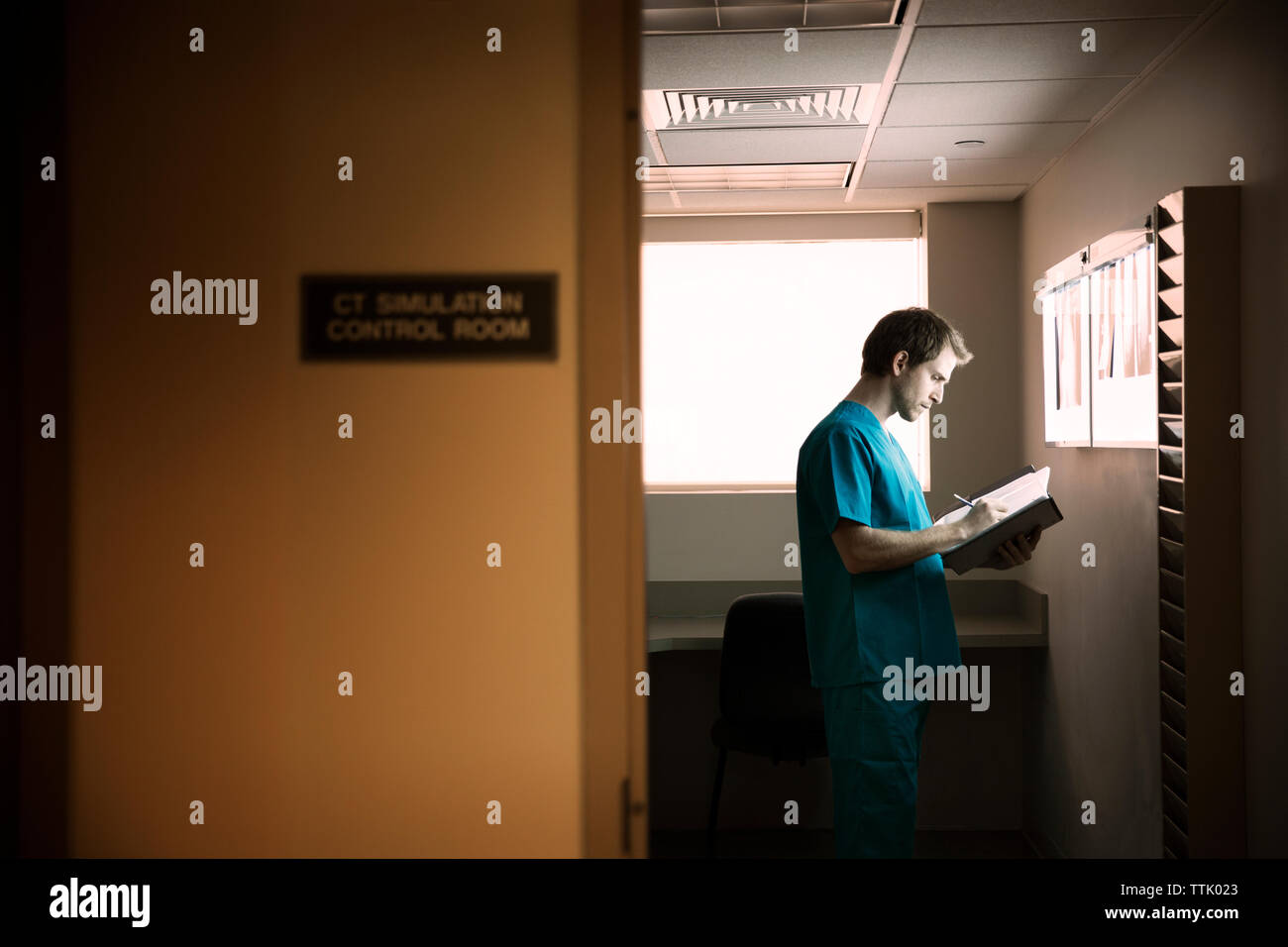 Lecture des rapports tout médecin standing in hospital ward Banque D'Images