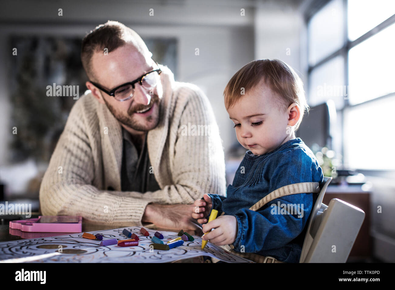 Smiling père parler en tirant à sa fille à table Banque D'Images