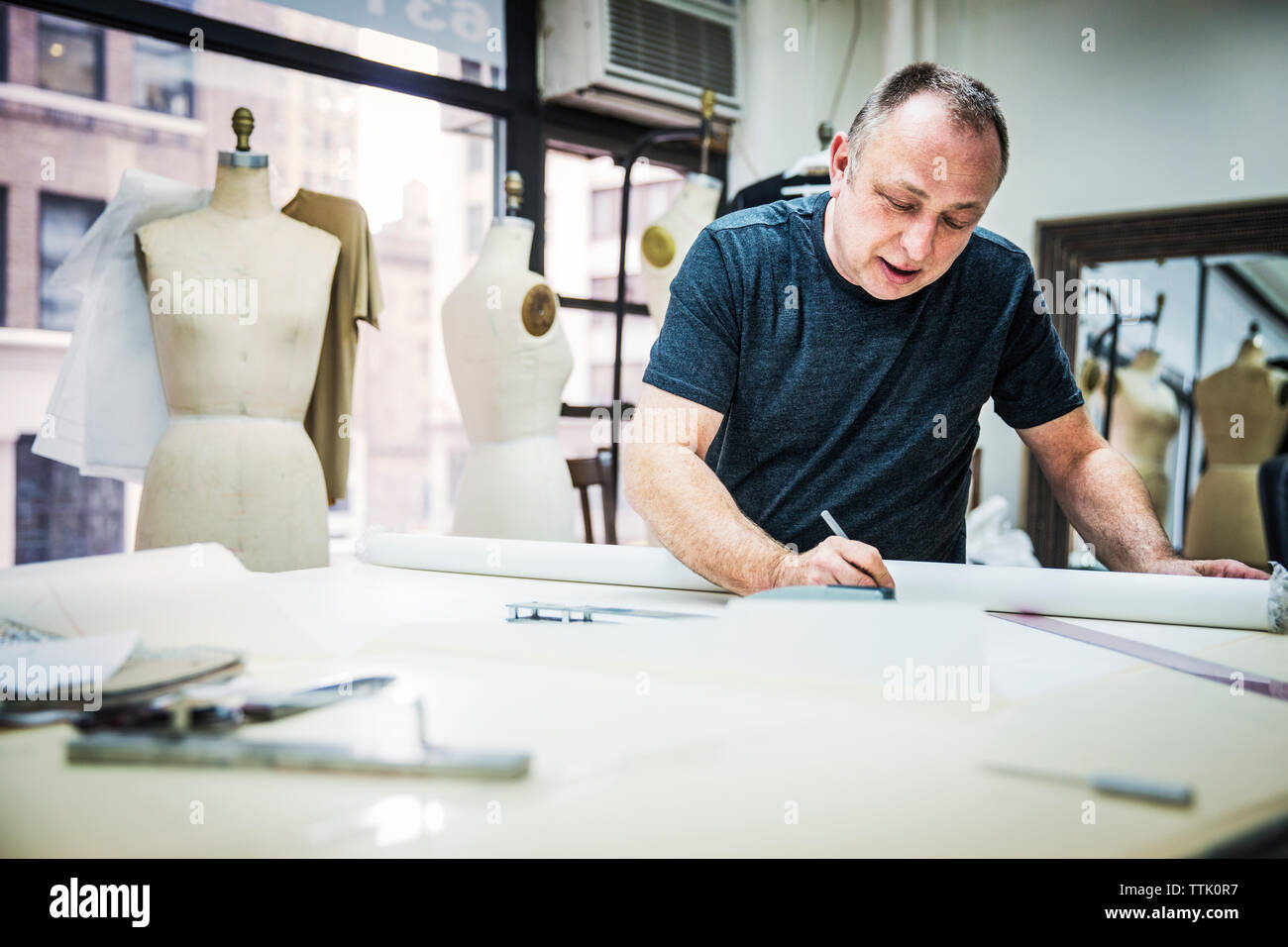 Créateur de mode sérieux working at table in design studio Banque D'Images