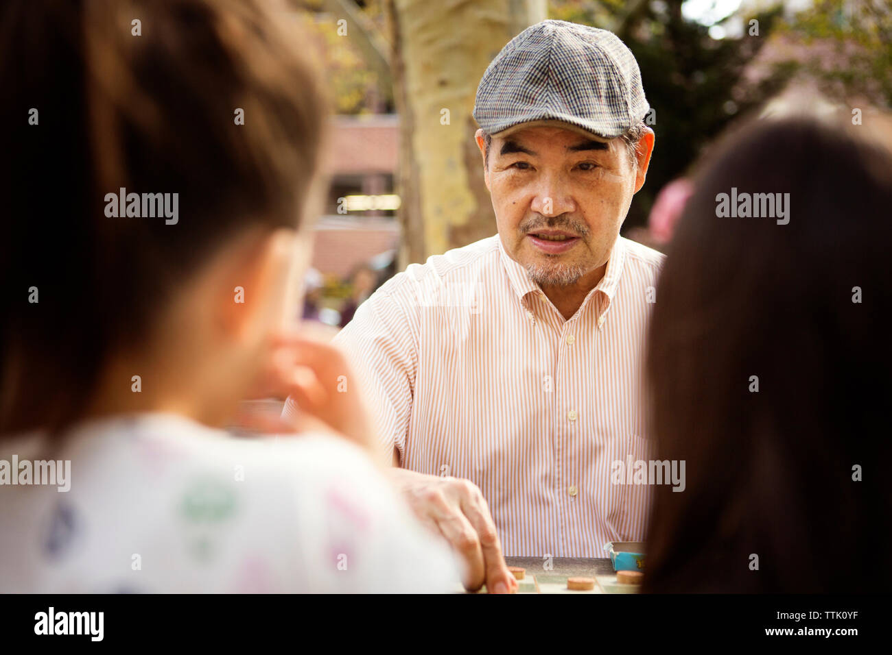 Grand-père jouer aux dames jeu alors que sitting at table in park Banque D'Images