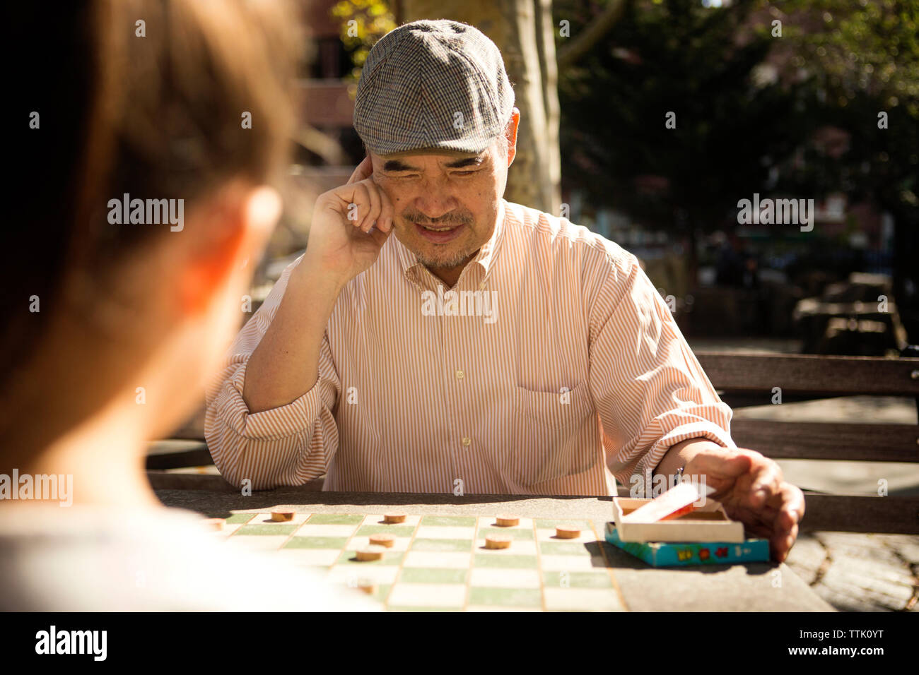 Happy man playing checkers jeu avec sa petite-fille à table dans park Banque D'Images