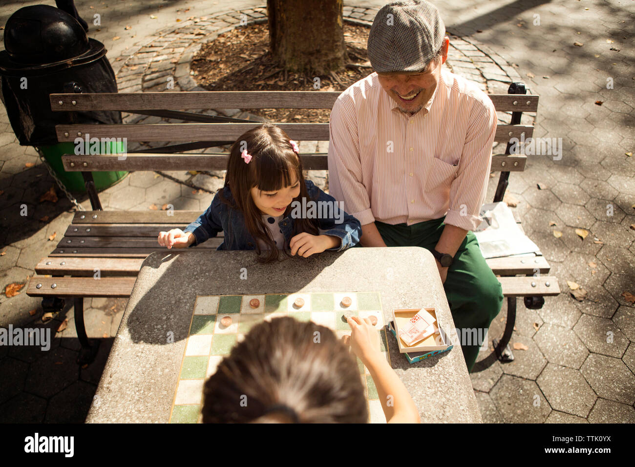 Portrait de grand-père à la recherche de filles à jouer aux dames en jeu park Banque D'Images
