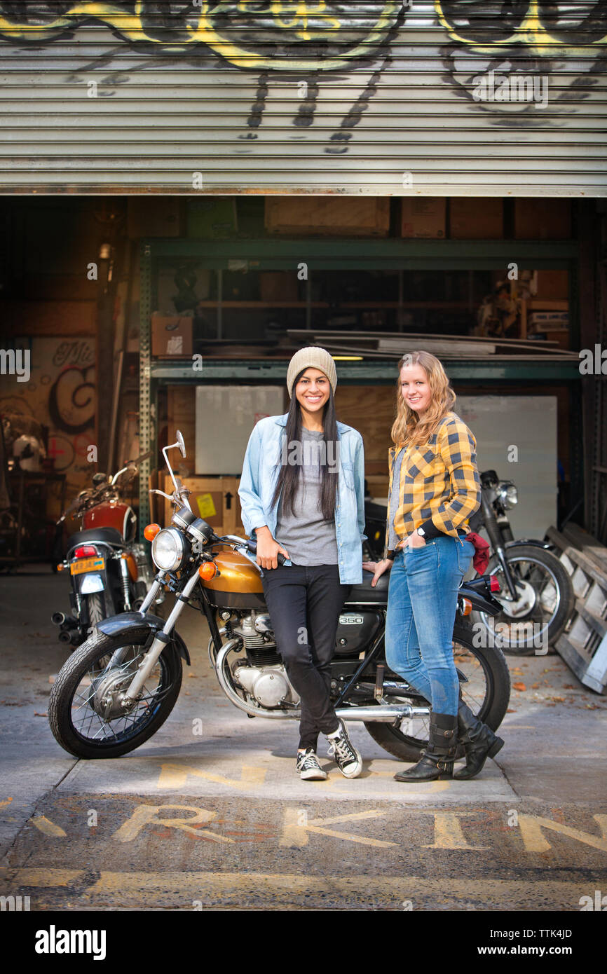 Portrait de Professionnels à des femmes debout avec l'extérieur vélo auto repair shop Banque D'Images