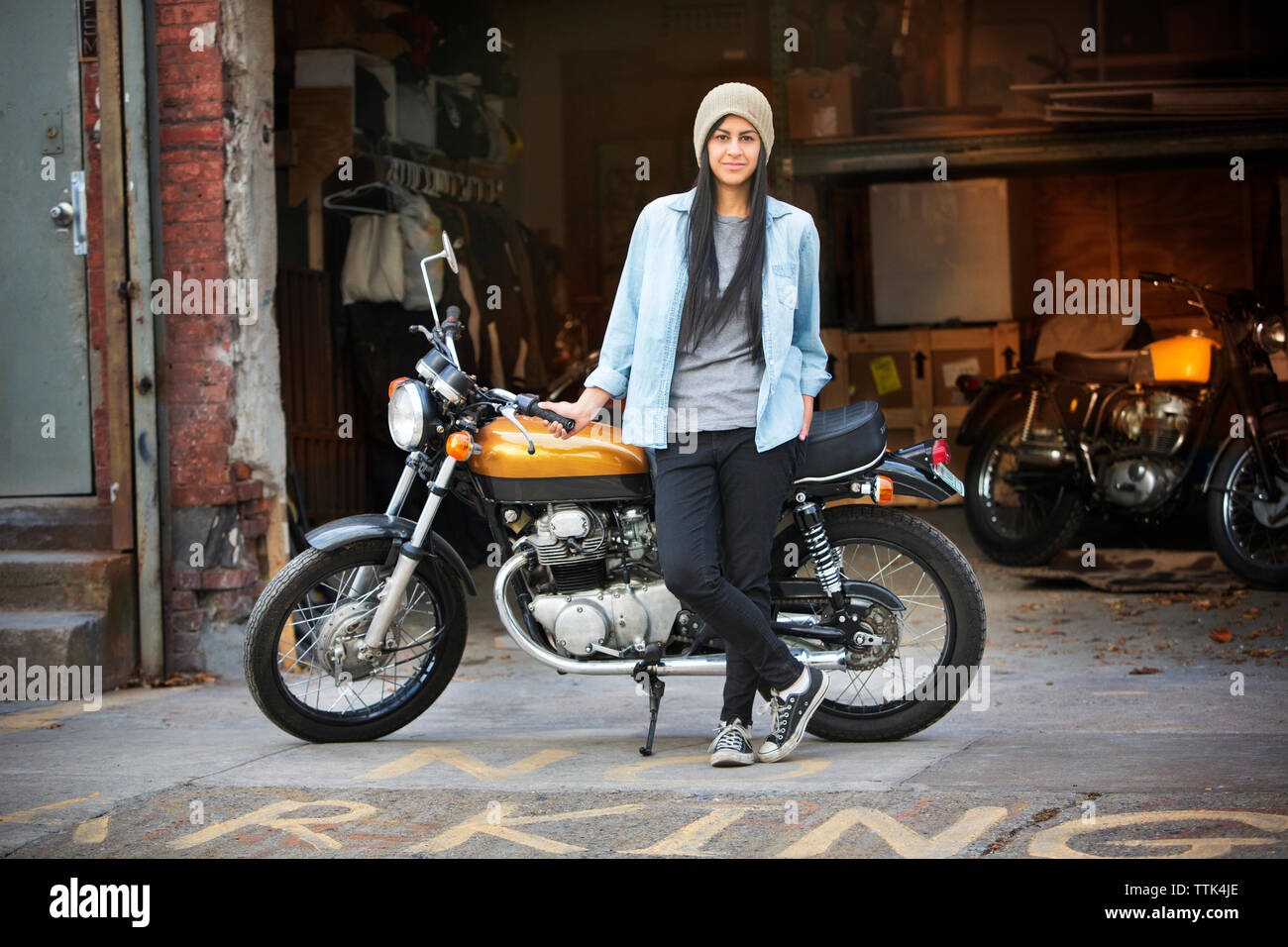 Portrait de femme debout avec le vélo à l'extérieur atelier de réparation automobile Banque D'Images