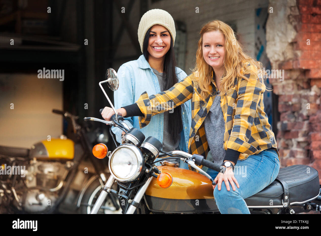 Portrait of smiling female friends avec le vélo à l'extérieur atelier de réparation automobile Banque D'Images