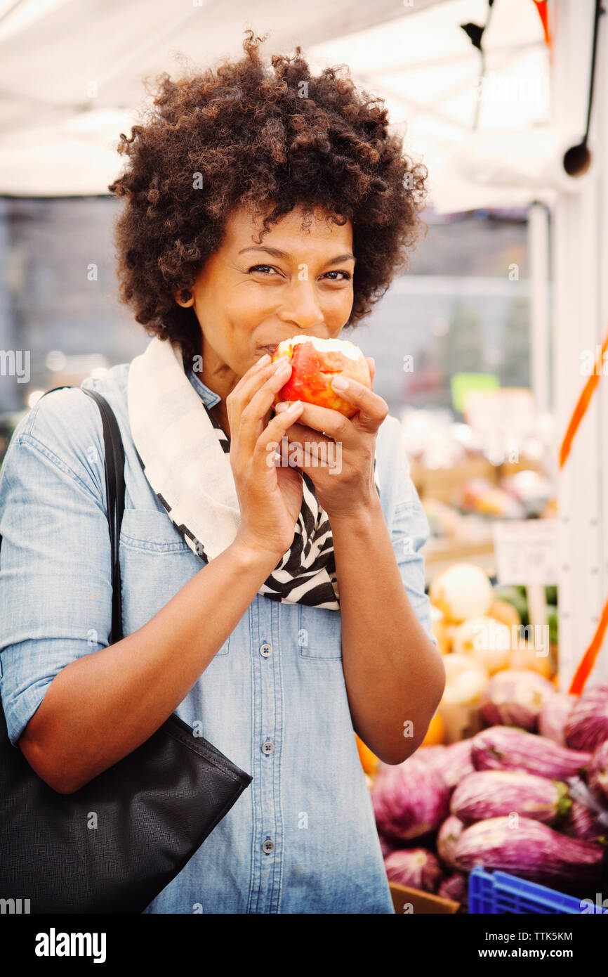 Portrait of woman eating apple en market Banque D'Images