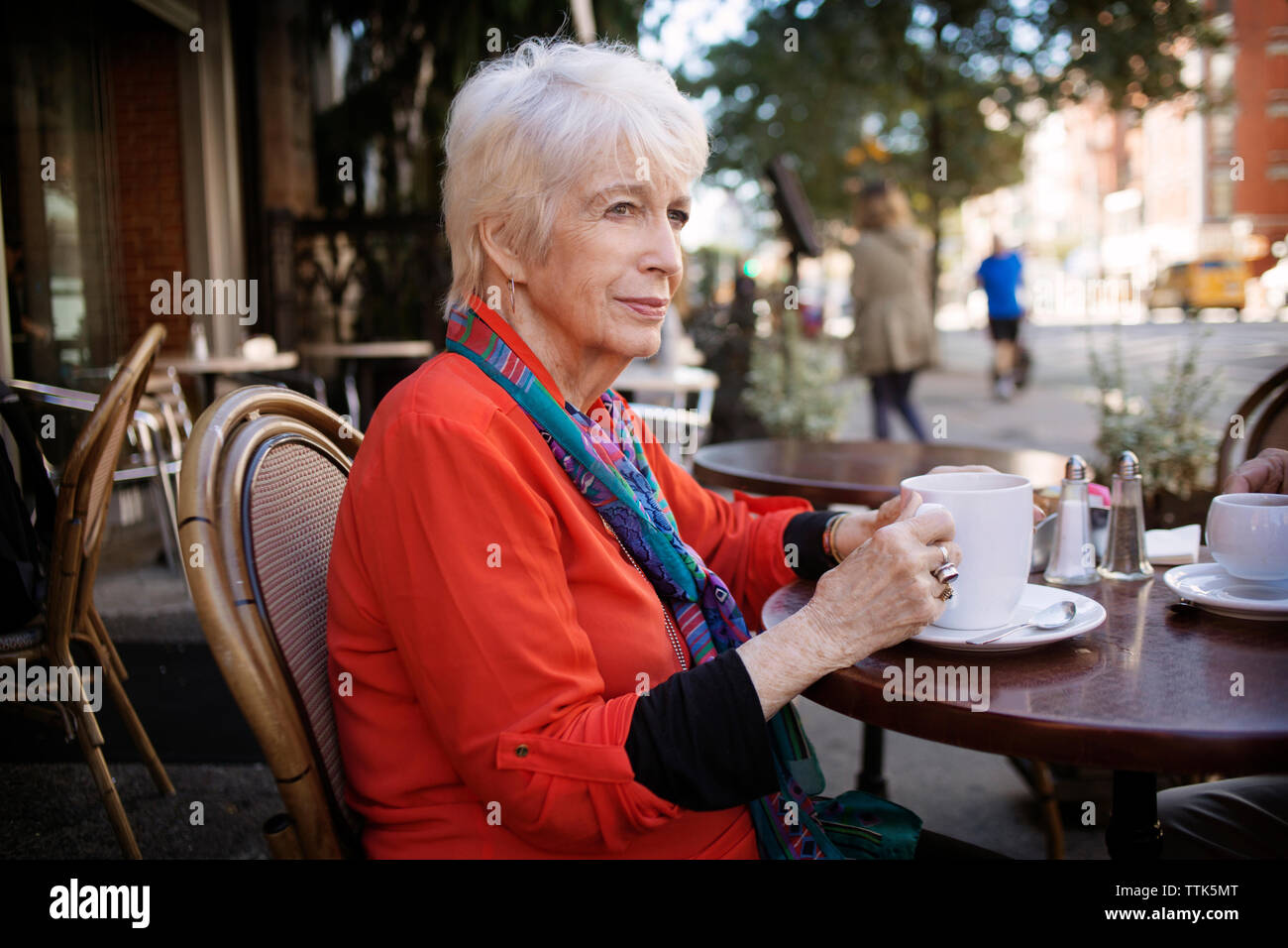 Happy woman holding Coffee cup while sitting at sidewalk cafe Banque D'Images Happy woman holding Coffee cup while sitting at sidewalk cafe Banque D'Images