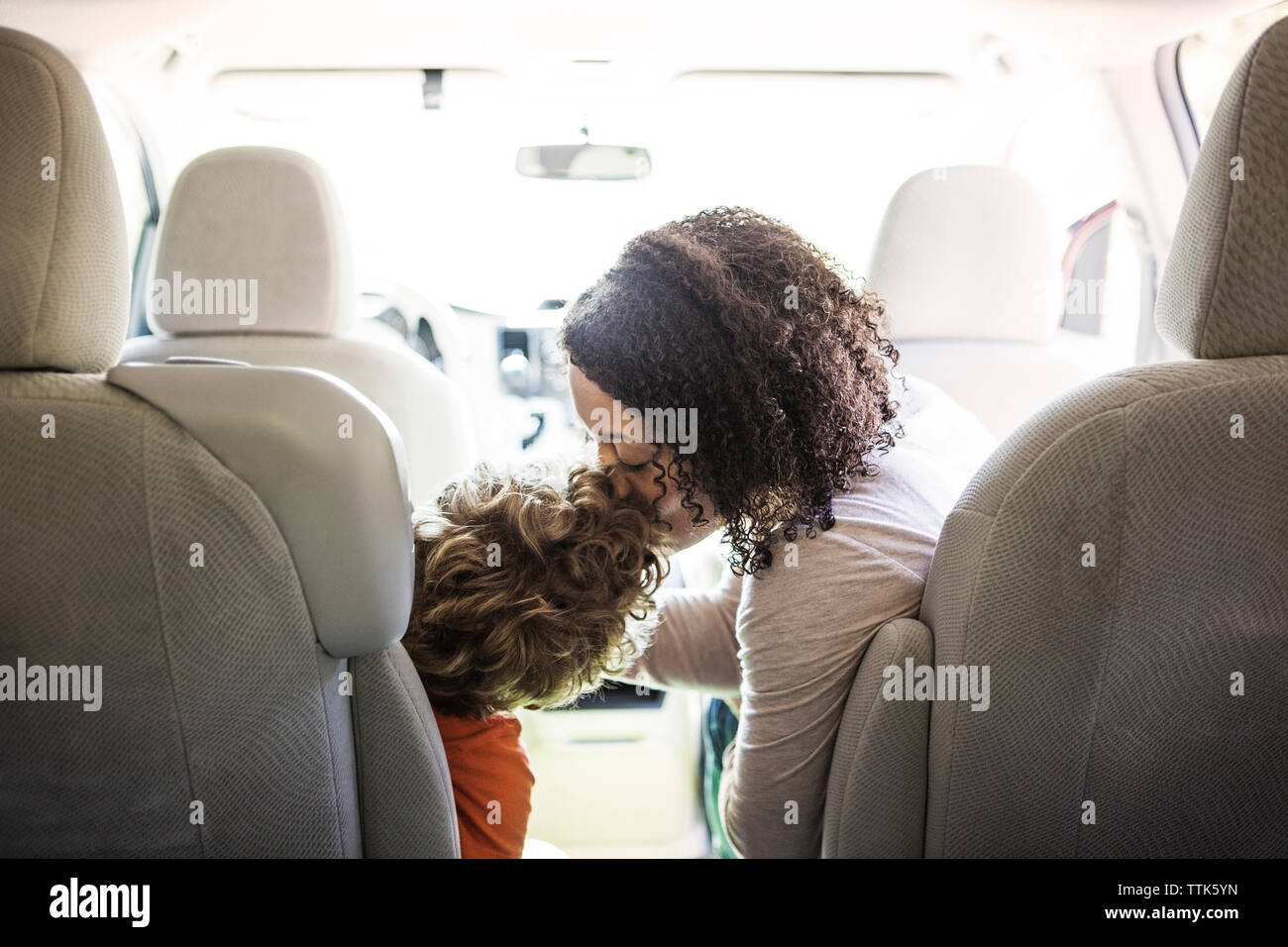 Mère embrassant son fils sur le front en voiture Banque D'Images