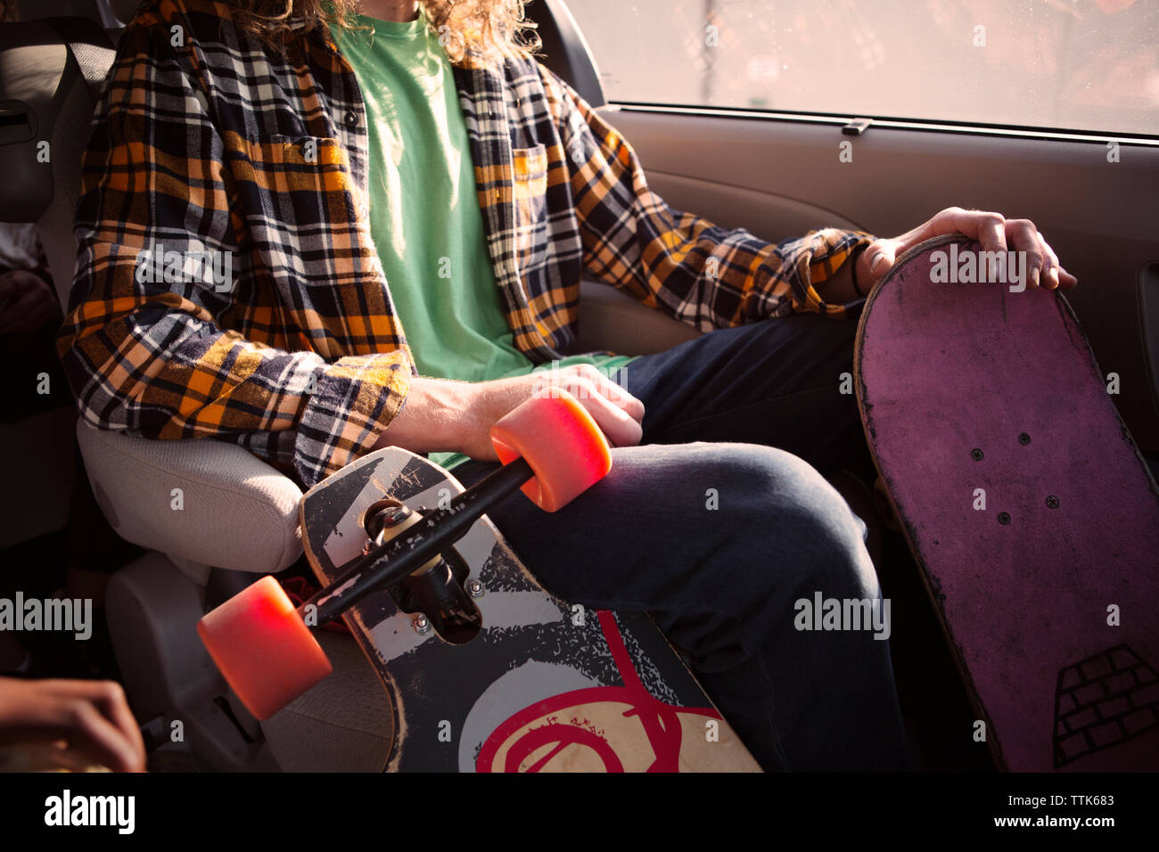 Portrait de l'homme assis dans la voiture avec des planches à roulettes Banque D'Images