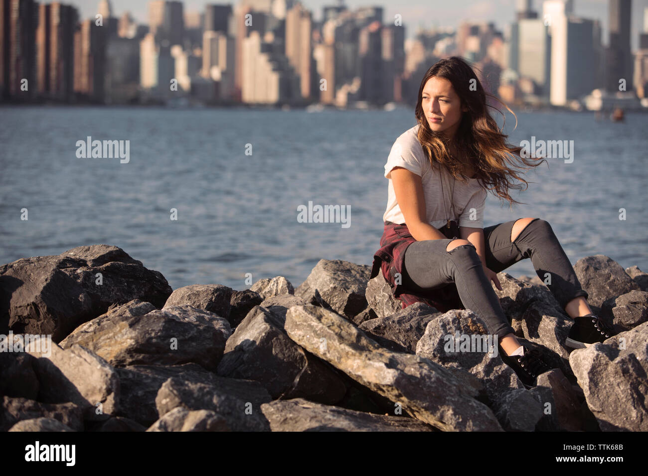 Thoughtful woman sitting on rocks par beach Banque D'Images