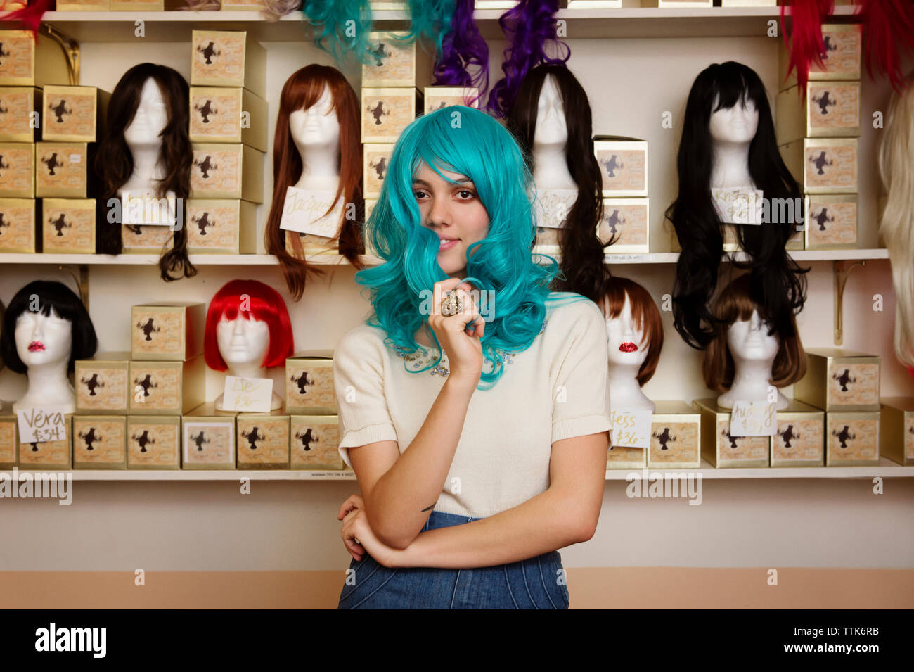 Portrait de femme portant perruque bleu debout contre les mannequins par store Banque D'Images