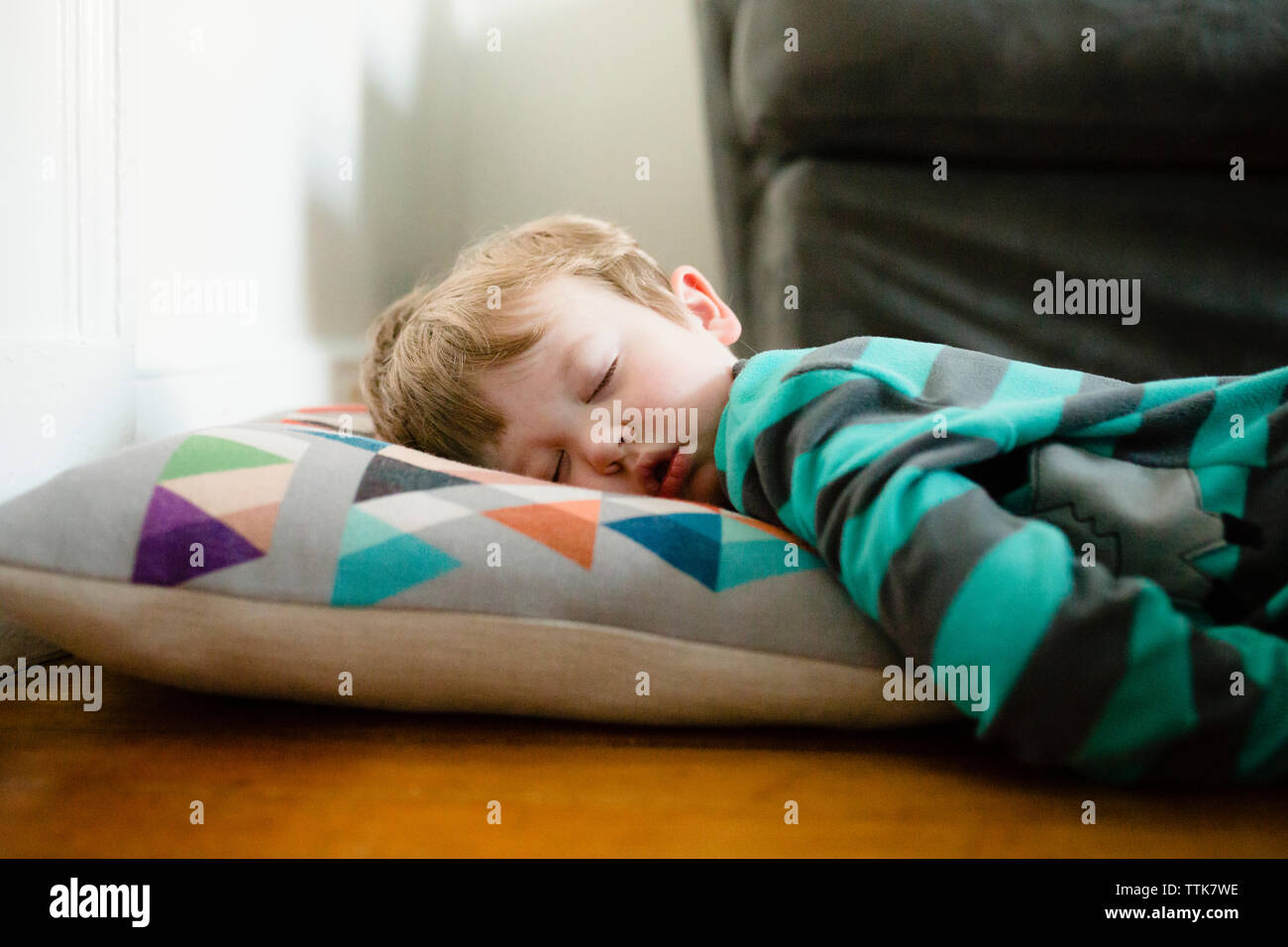 Fatigué garçon endormi sur le plancher à la maison Banque D'Images