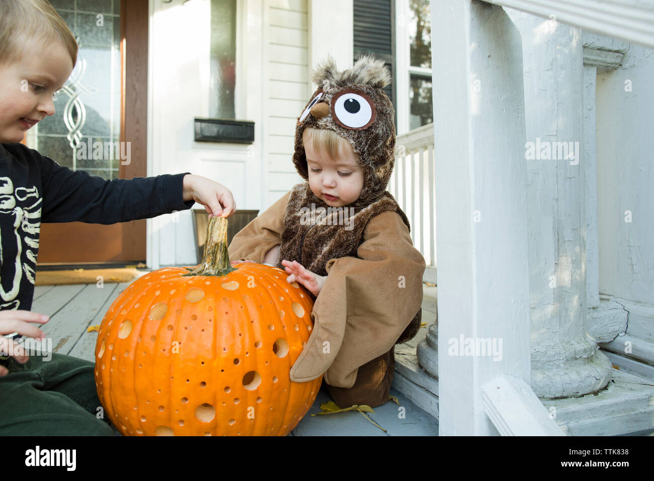 Deux enfants examiner jack o lantern sur porche à l'Halloween Banque D'Images