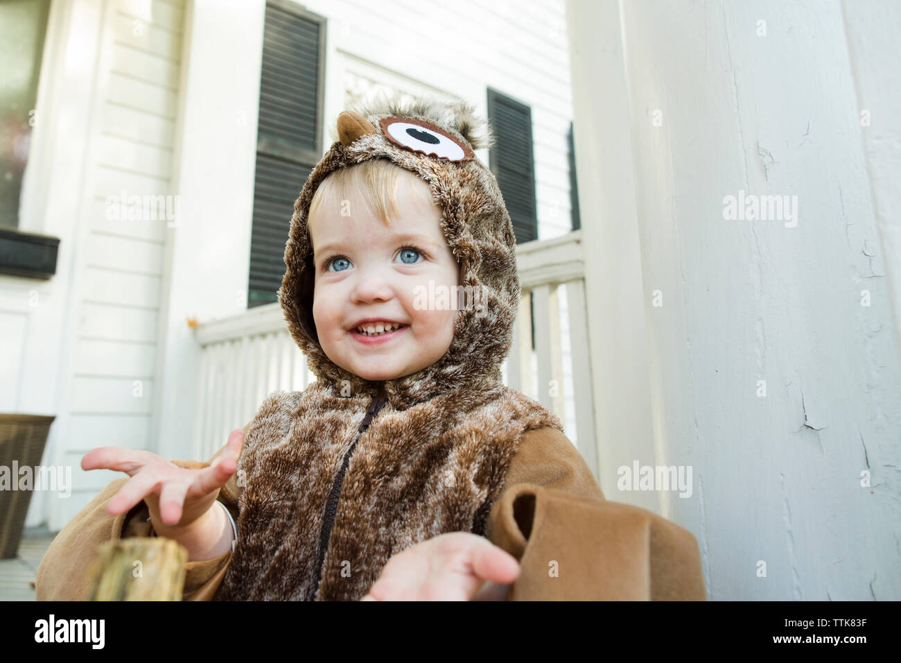 Blue Eyed toddler offre des mains en souriant tout en s'habillant comme un hibou Banque D'Images