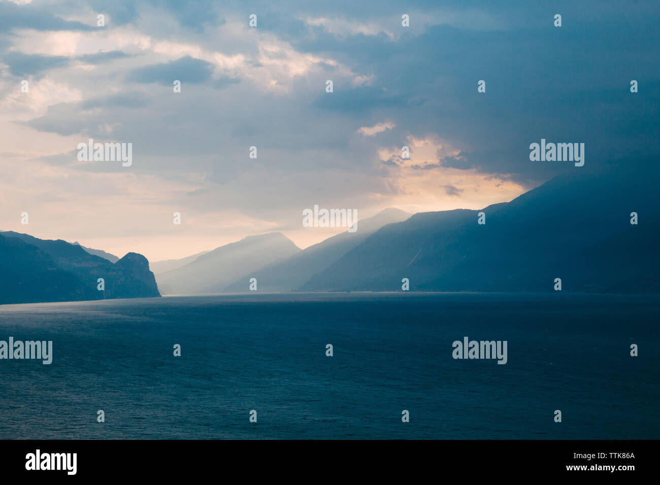 Lever du soleil les rayons de lumière briller au-dessus des montagnes sur le lac de Garde en Italie Banque D'Images