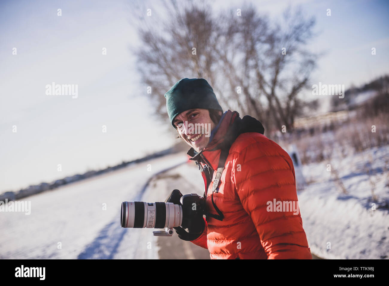 Photographe à la recherche de l'appareil photo en souriant dans le froid avec zoom et d'un reflex numérique Banque D'Images