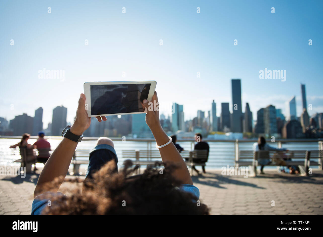 L'homme à l'aide de tablet en position couchée sur le banc contre cityscape Banque D'Images