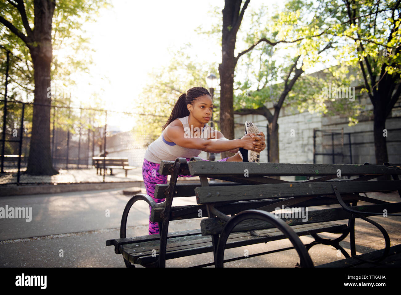 Woman stretching sur banc en bois du park Banque D'Images