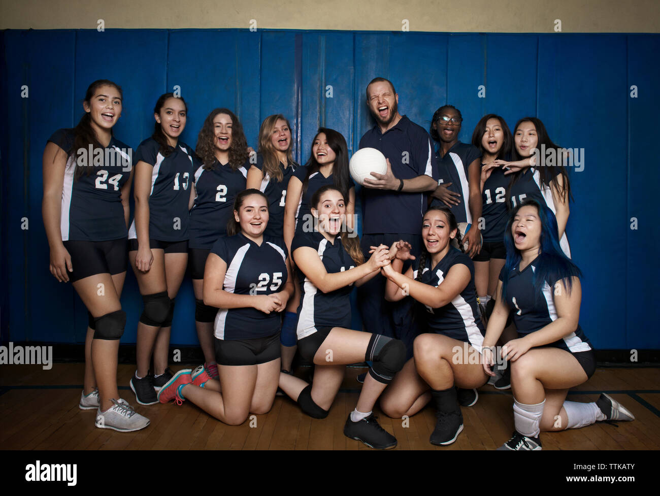 L'équipe de volley-ball de crier contre l'Heureux mur bleu Banque D'Images