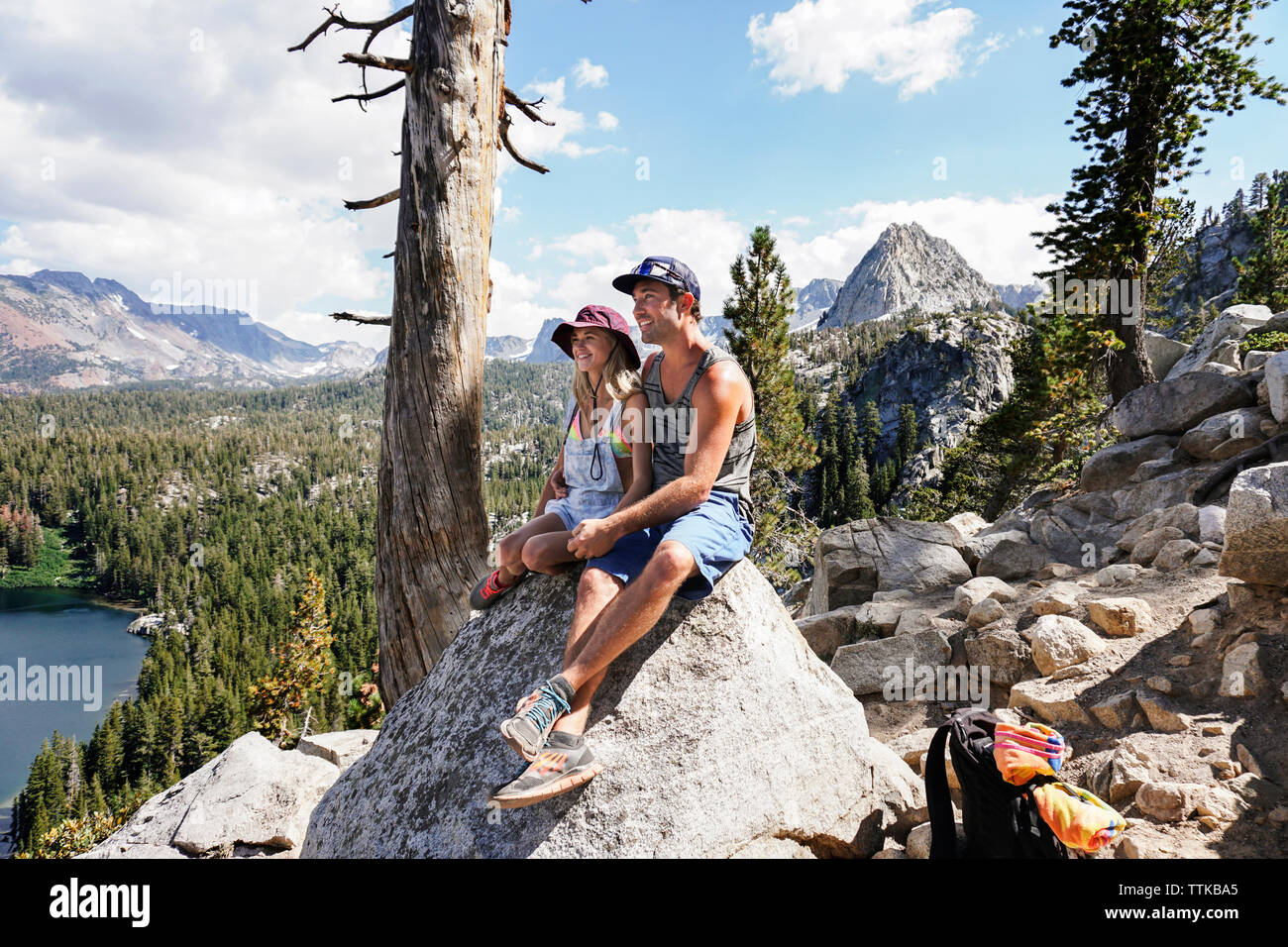 Couple looking at view, assis sur des pierres contre le ciel Banque D'Images