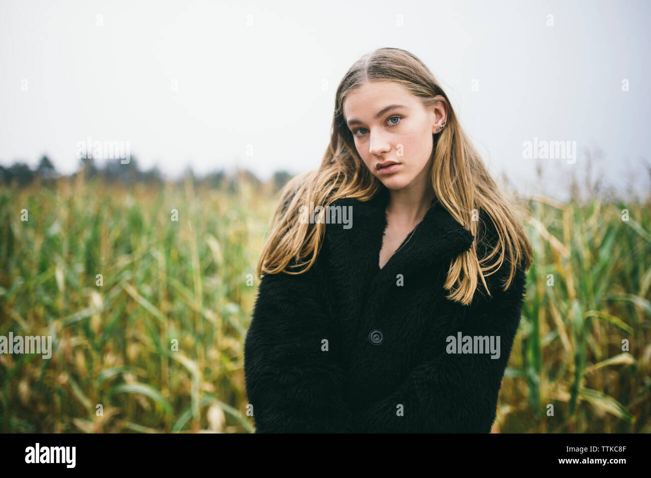 Femme se trouve dans un champ de maïs par temps nuageux Banque D'Images