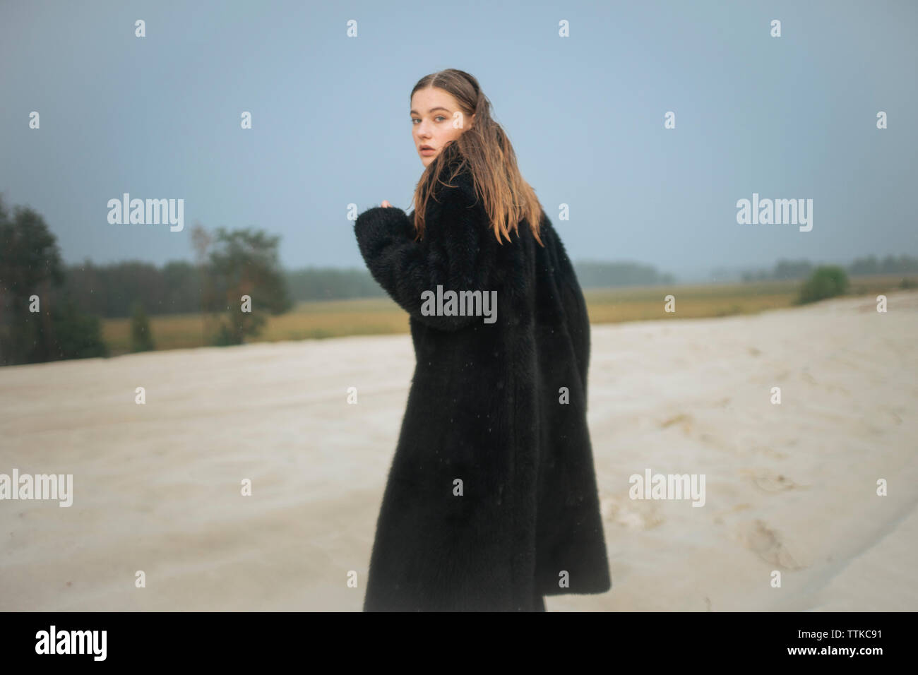 Femme dans un manteau de fourrure sur le sable tourne autour de Banque D'Images
