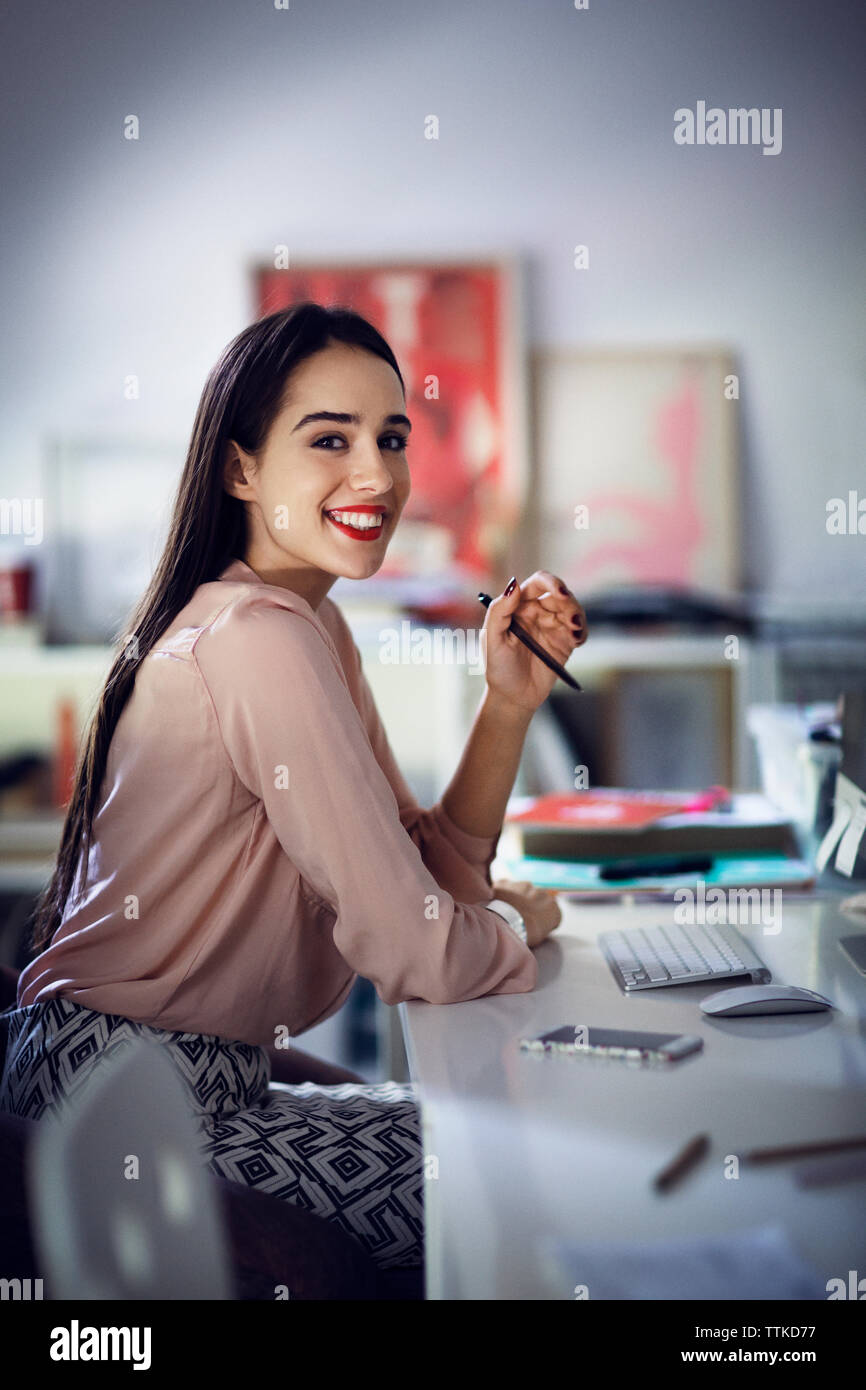 Portrait of smiling businesswoman sitting at desk in office Banque D'Images