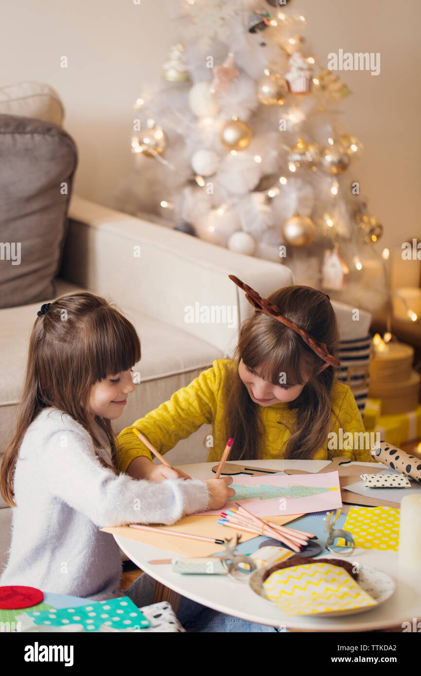 Frères et sœurs dessinant l'arbre de noël sur papier à la maison Banque D'Images