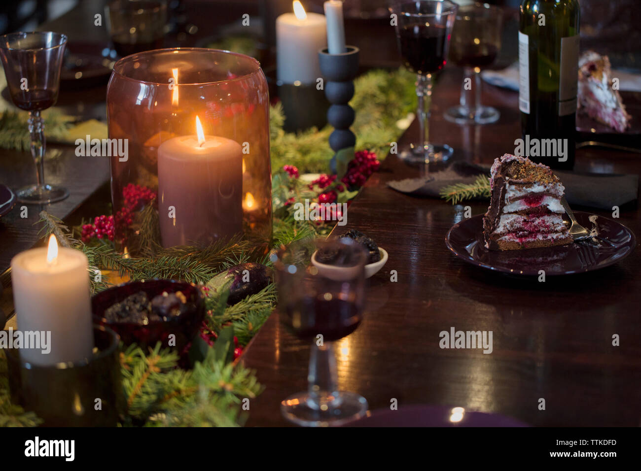 Dessert et verres à vin sur la table à manger illuminée pendant noël Banque D'Images