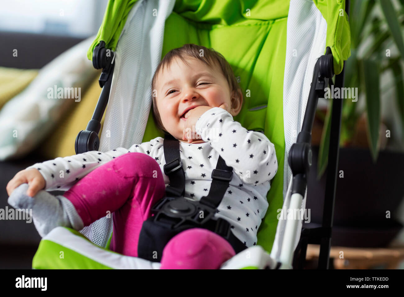 Happy baby girl sitting in transport à la maison Banque D'Images