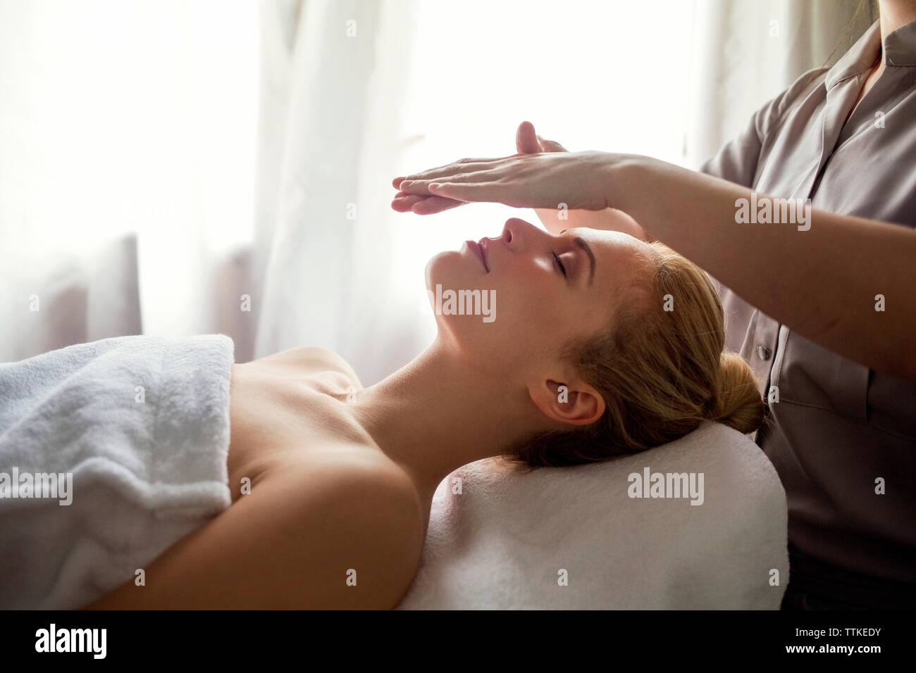 Au milieu du traitement Reiki thérapeute donnant à la femme sur le visage au spa Banque D'Images