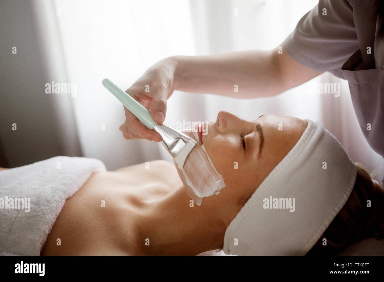 Au milieu de l'application de masque facial thérapeute sur femme à spa Banque D'Images