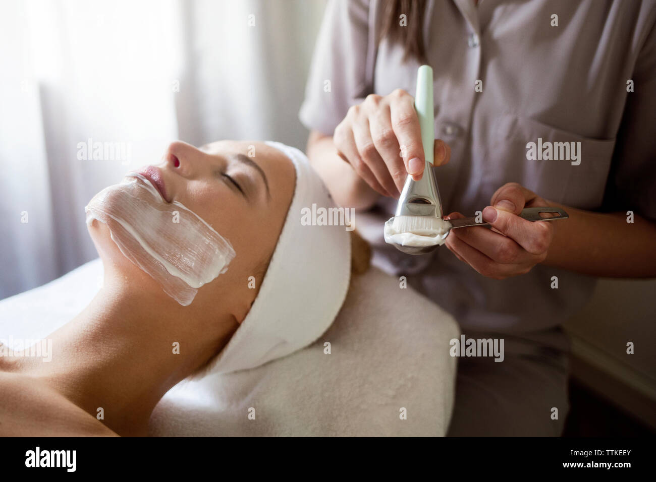 Au milieu de l'application de masque facial thérapeute on woman Banque D'Images
