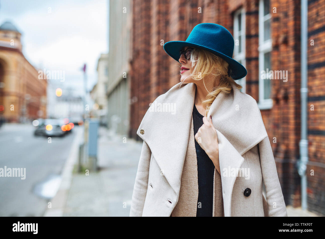 Manteau femme portant à l'écart en se tenant sur le trottoir en ville Banque D'Images