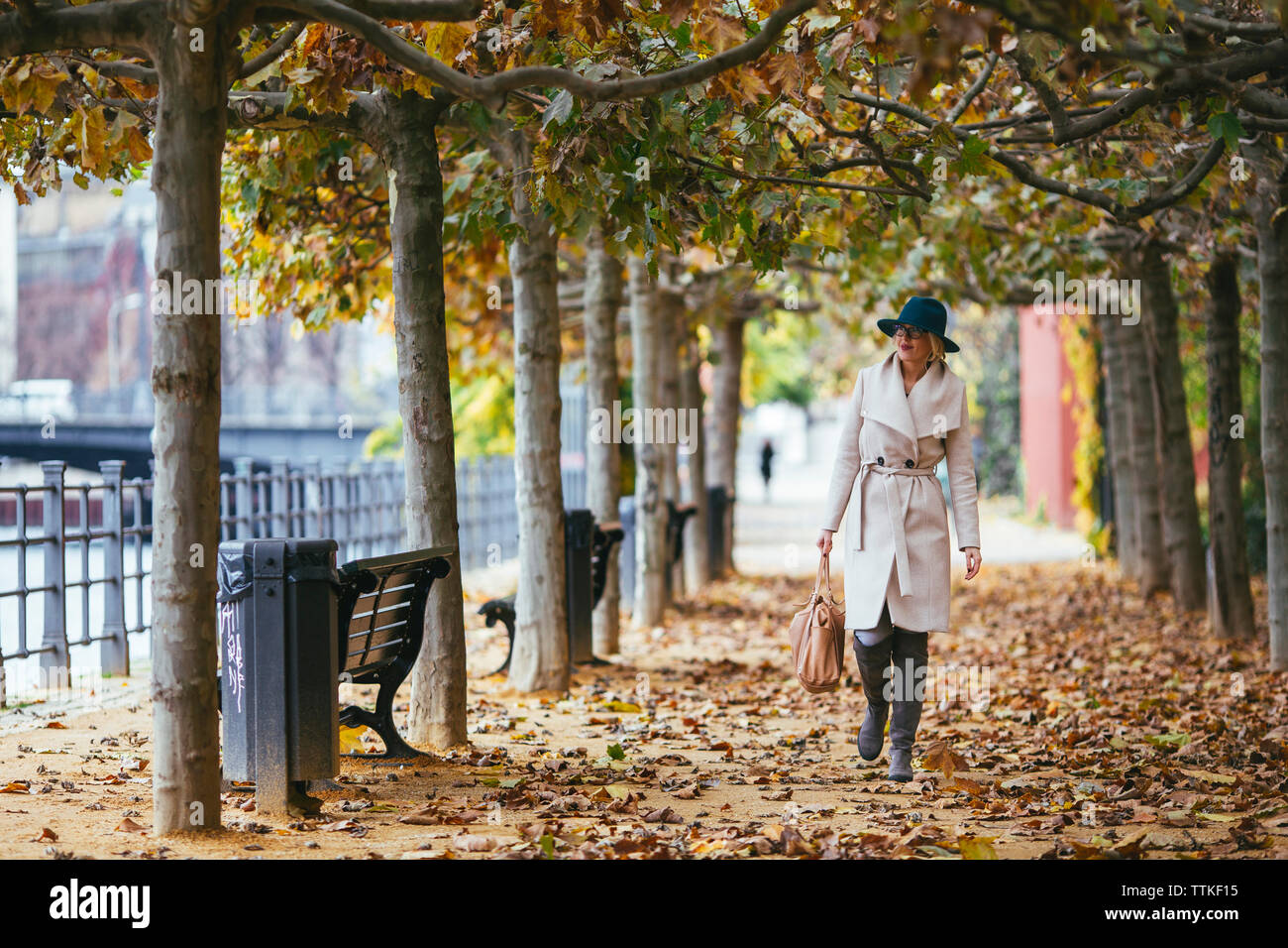 Manteau femme portant la marche sur sentier dans le parc en automne Banque D'Images