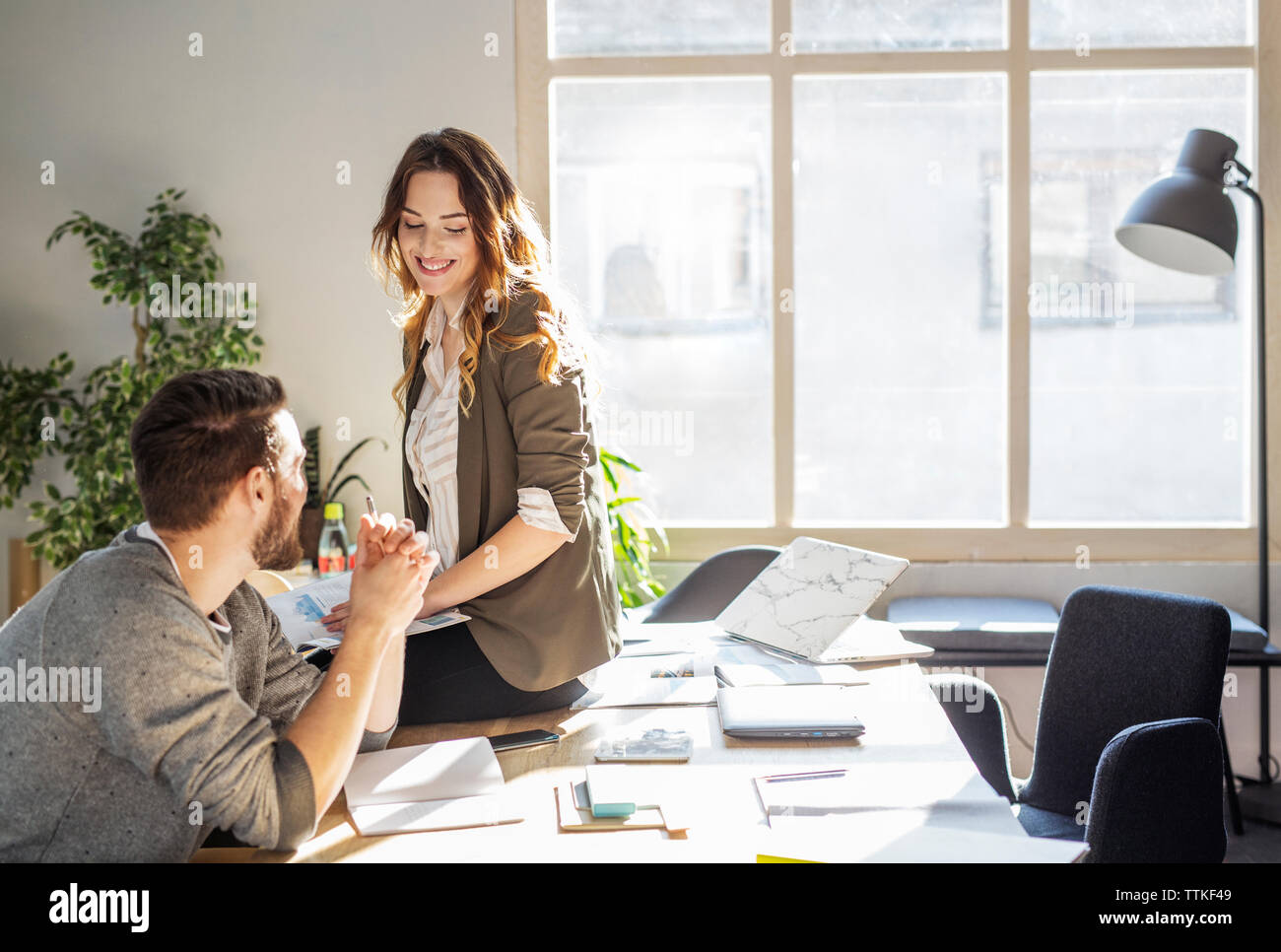 Happy friends talking while sitting at table in classroom Banque D'Images