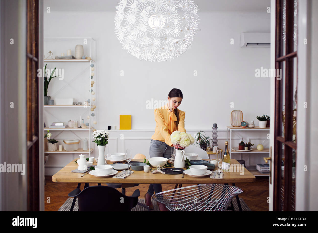 L'organisation de femme fleurs à table à manger dans la maison Banque D'Images