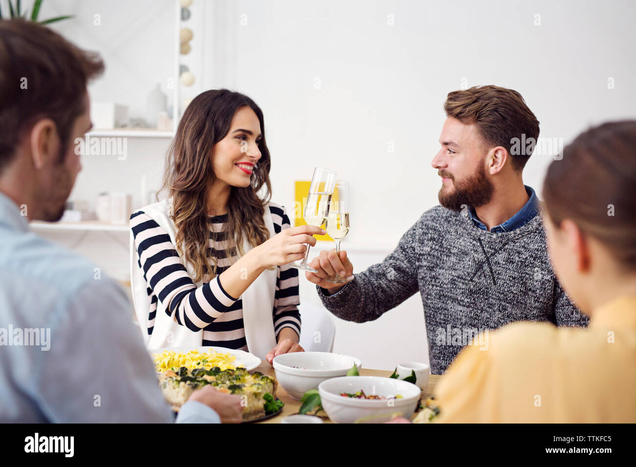 Smiling friends raising toast célébration à table à manger Banque D'Images