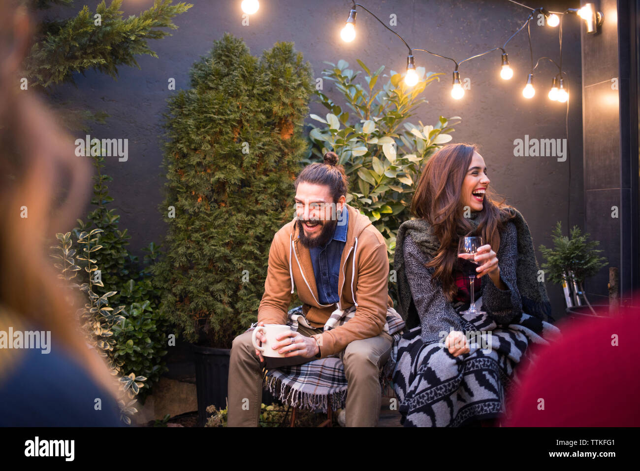 Cheerful friends enjoying drinks while sitting in backyard Banque D'Images